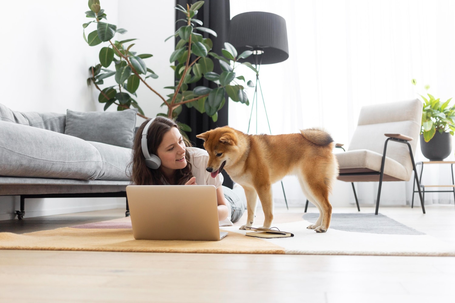 Woman working on laptop with dog standing next to her and watching